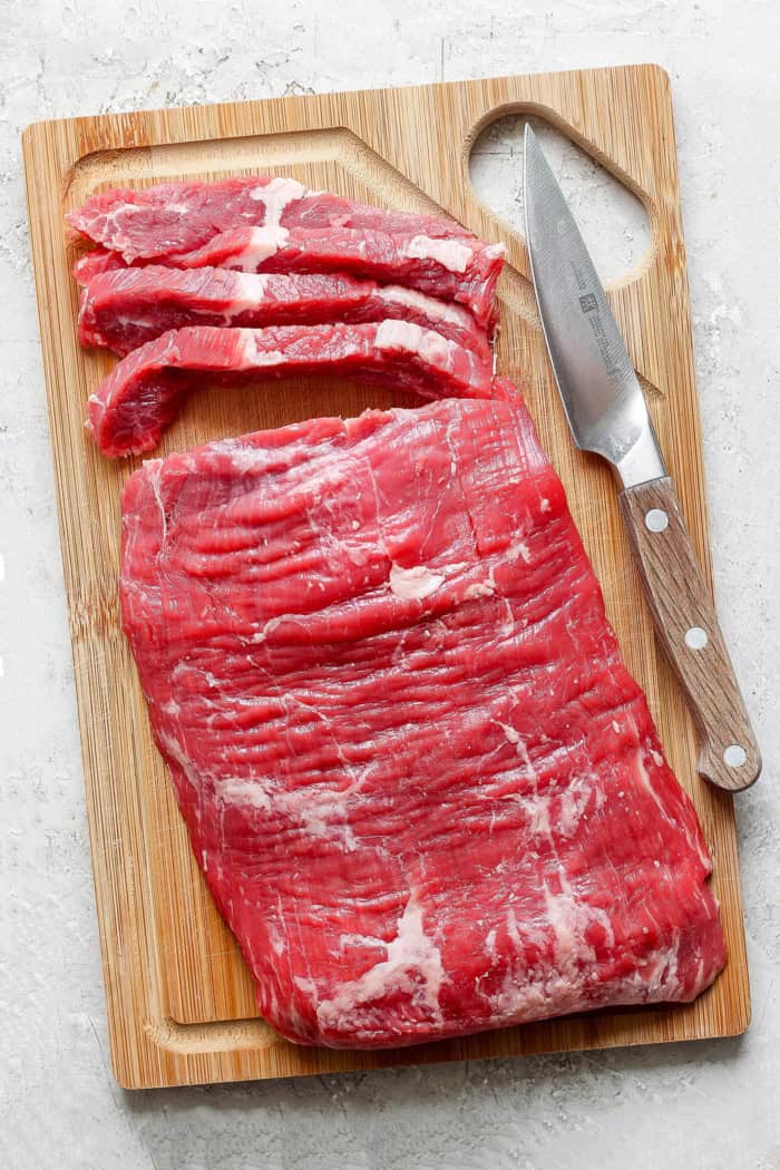 Beef on wooden cutting board with knife, with 4 slices cut