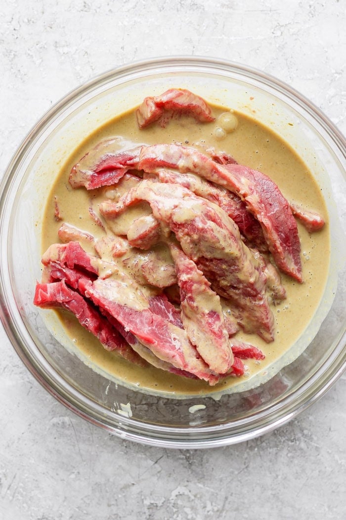 Sliced beef marinating in coconut milk mixture