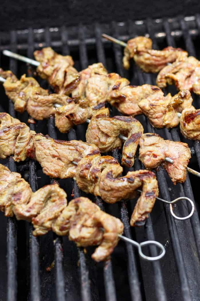 Coconut beef satay cooking on grill