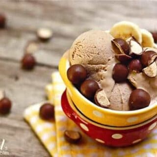 A bowl of chocolate ice cream with malted balls and banana slices