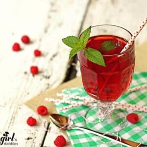 a glass cup of iced tea with fresh raspberries