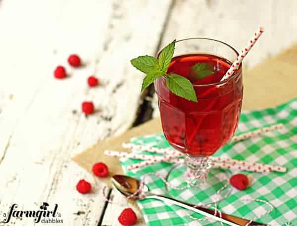 a glass cup of iced tea with fresh raspberries