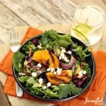 A bowl of grilled peach salad with grilled peaches and onions