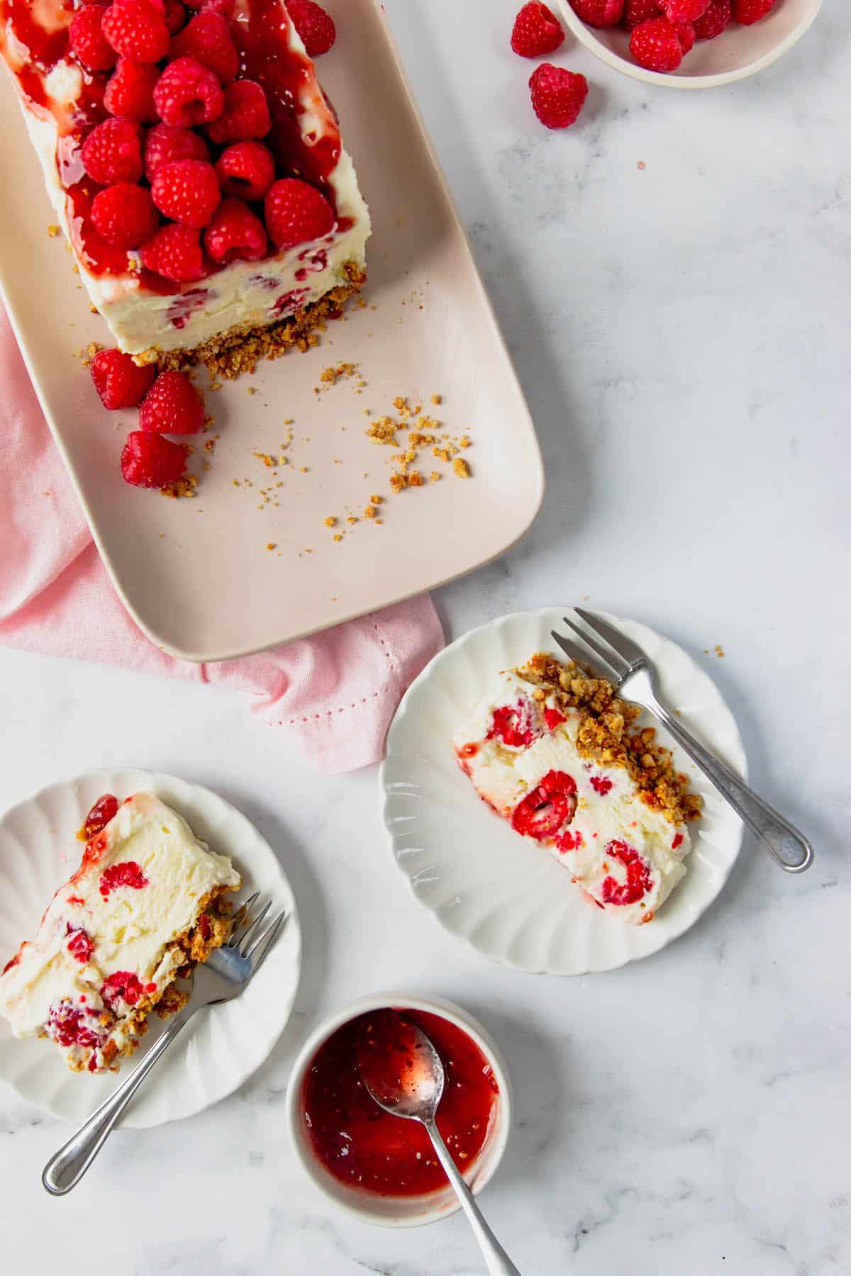 Overhead view of two white chocolate raspberry bars on white plates