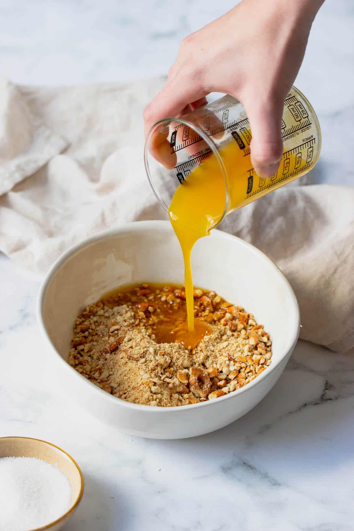 Melted butter being poured over pretzel crumbs