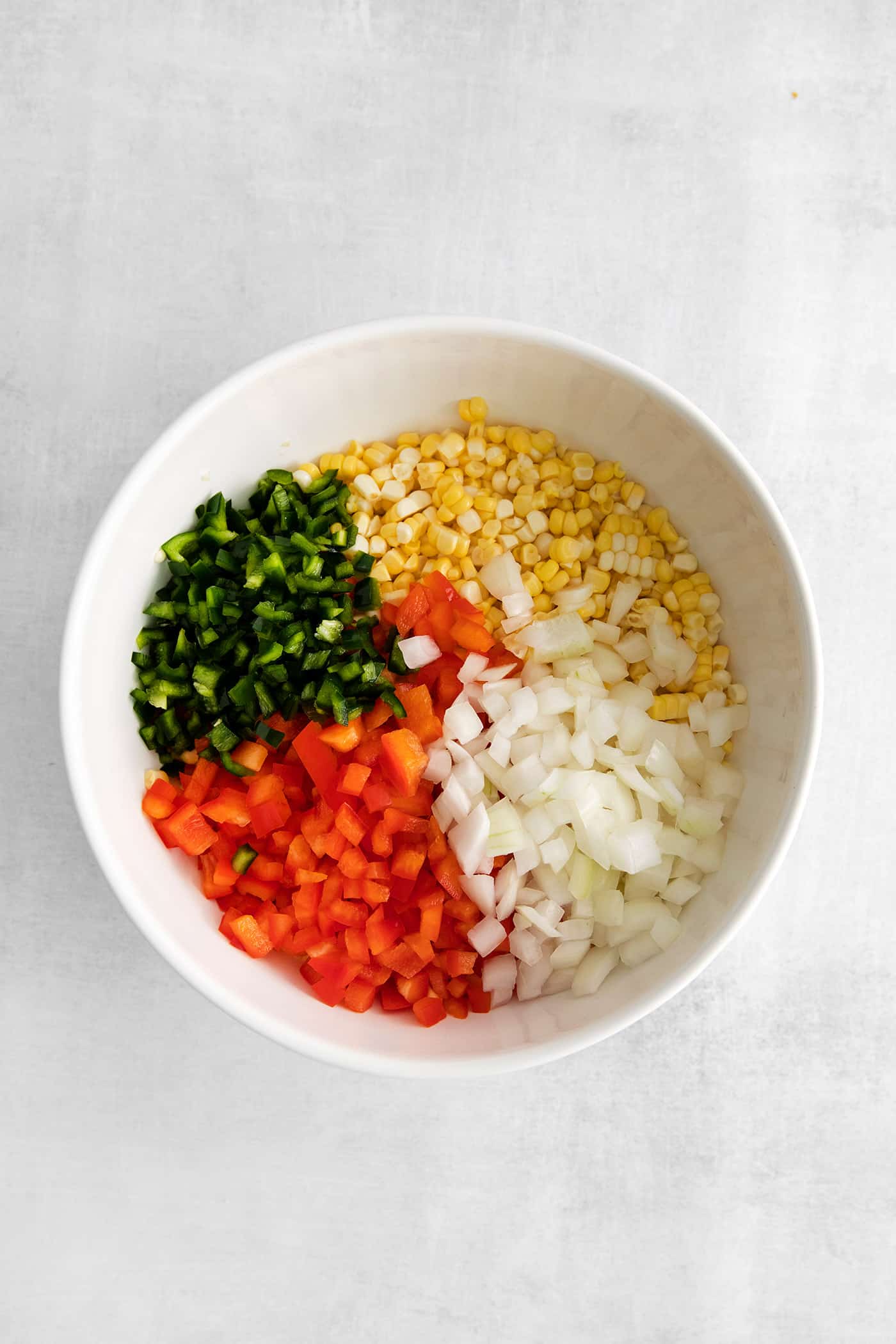 Corn, red peppers, poblano peppers, and onion in a bowl