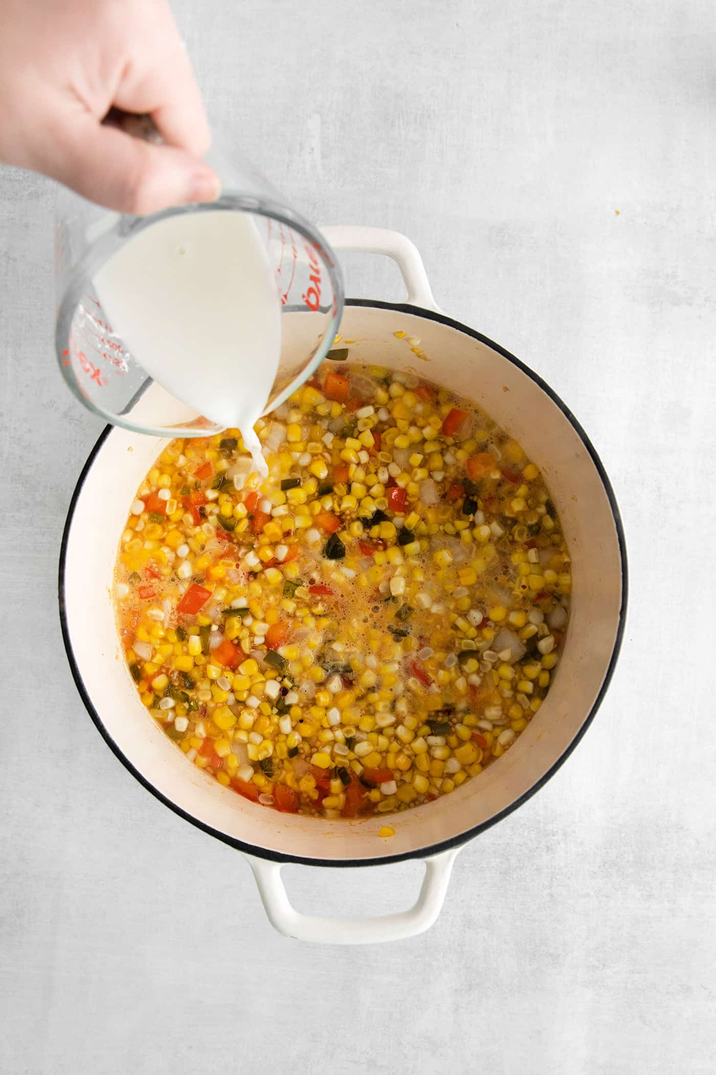 Cornstarch slurry being added to corn relish in a big pot