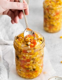 A spoon stirring a jar of sweet corn relish