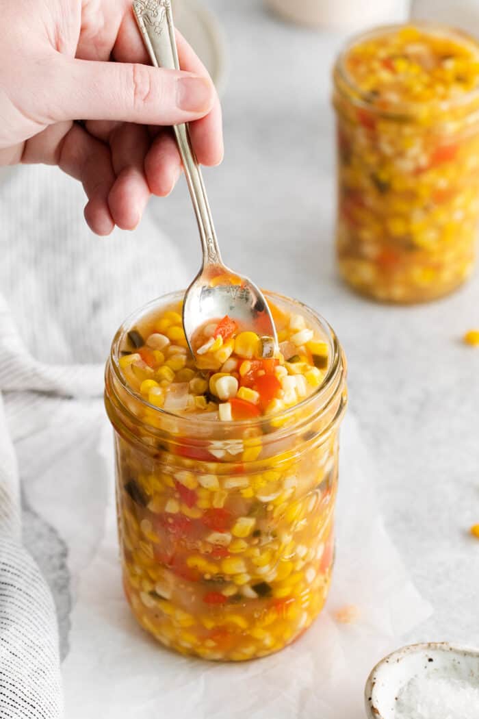 A spoon stirring a jar of sweet corn relish