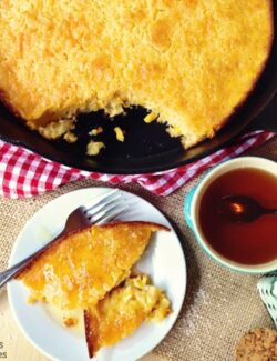 A skillet pan of Cornbake with a plate of a piece of it cut out.