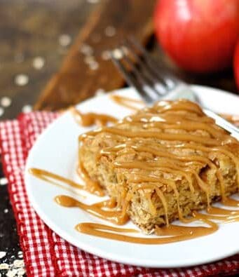 A Square Apple Oatmeal Bar on a Plate Beside Two Fresh Apples