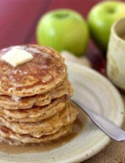 A Stack of Apple Pancakes on a Plate Next to a Cup of Coffee