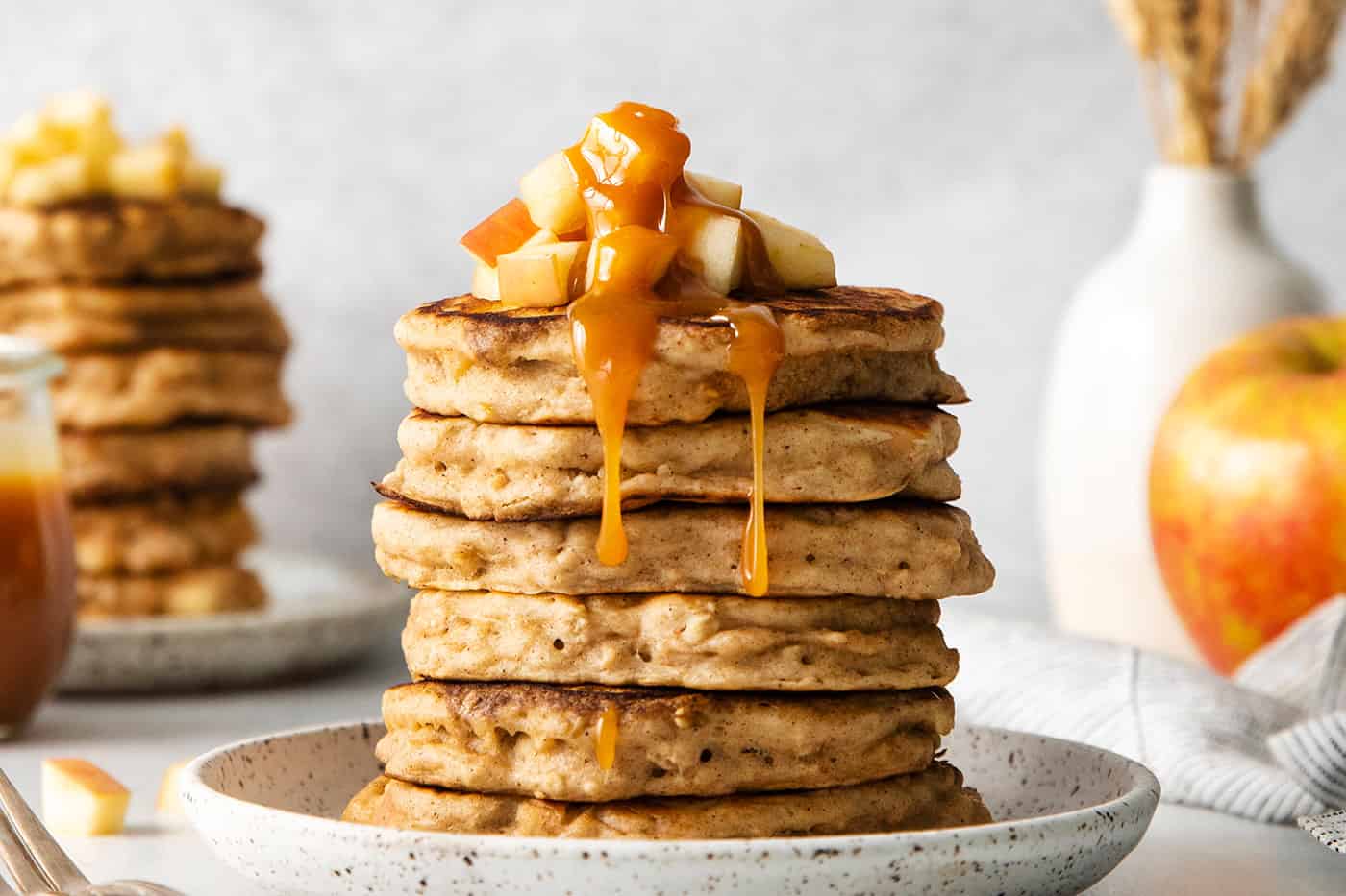 A stack of apple oatmeal pancakes topped with caramel buttermilk syrup
