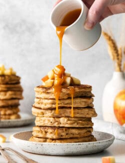 Caramel buttermilk syrup being poured over a stack of pancakes