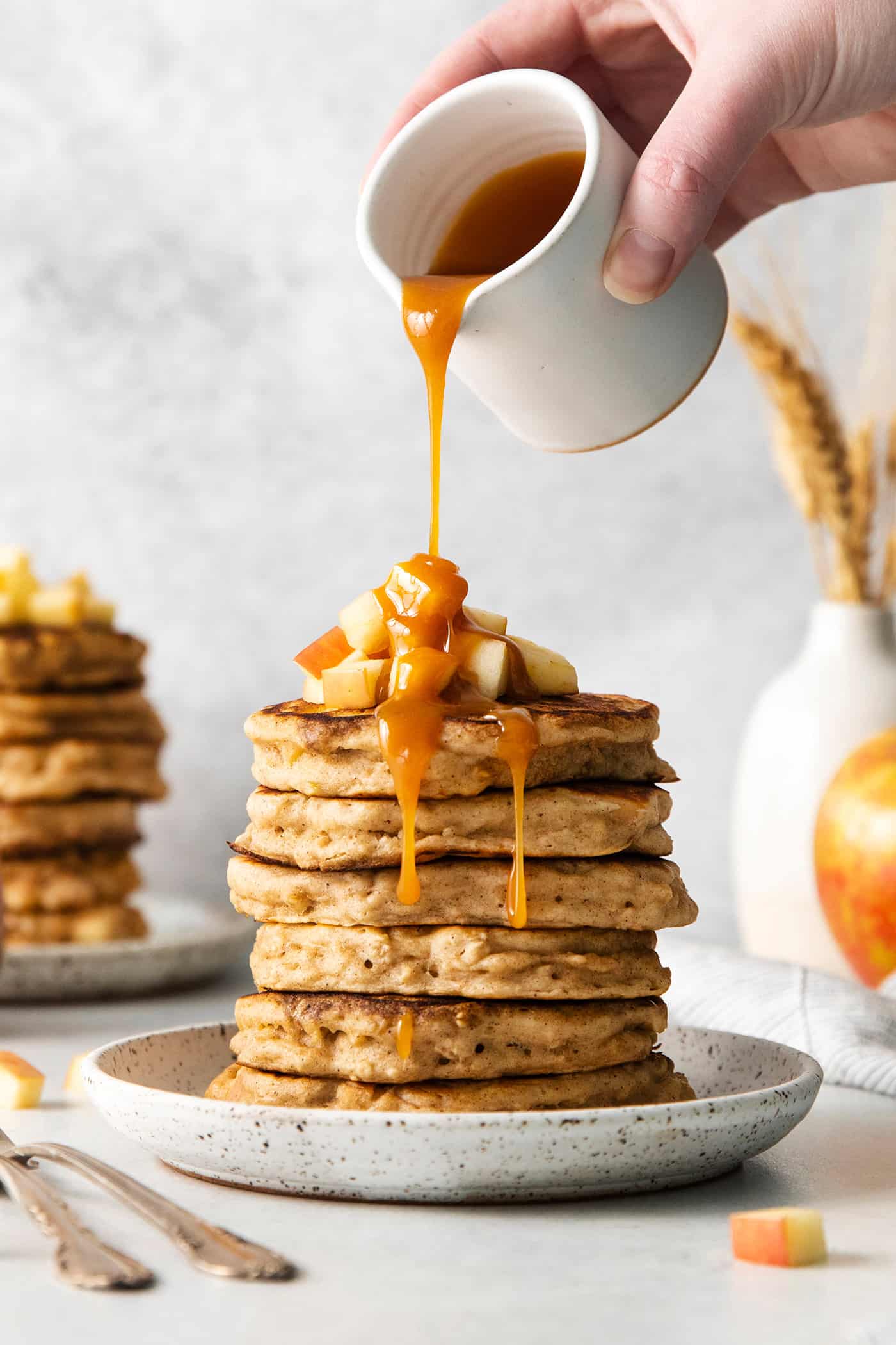 Caramel buttermilk syrup being poured over a stack of pancakes