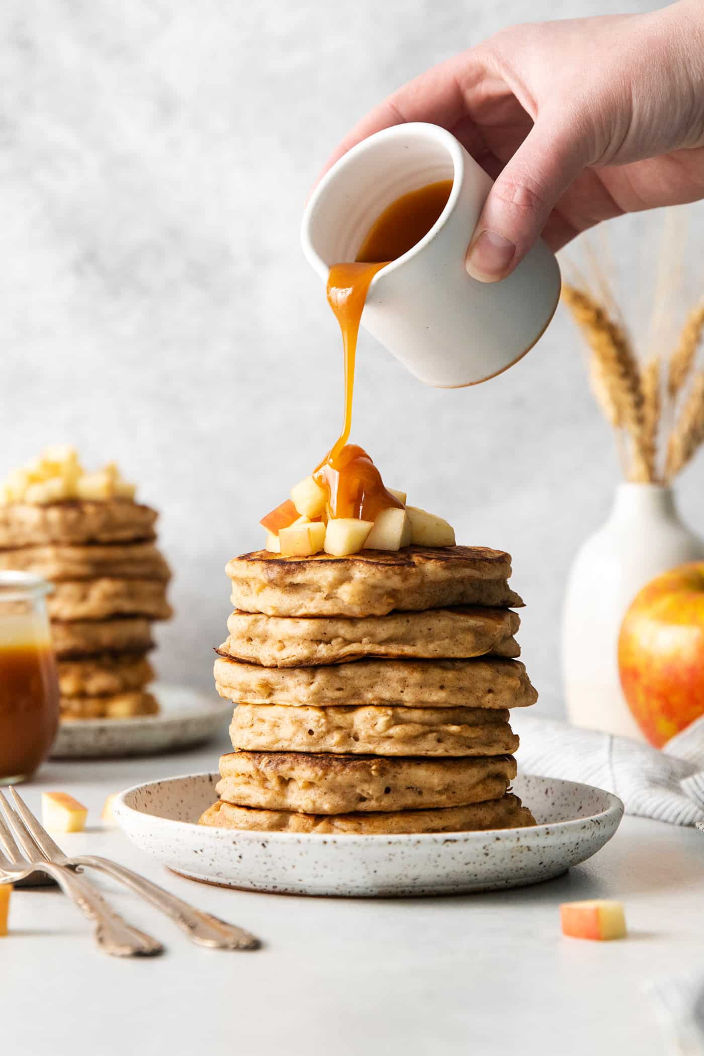 Caramel buttermilk syrup being poured over a stack of pancakes