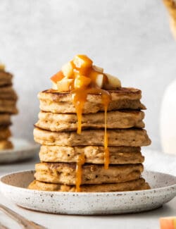 A stack of apple buttermilk pancakes on a white plate