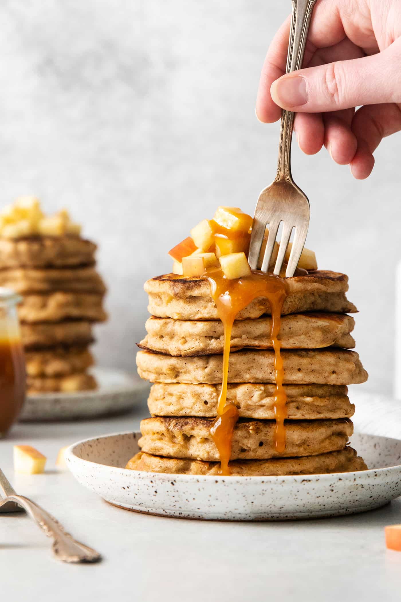 A fork diving into a stack of apple oat pancakes