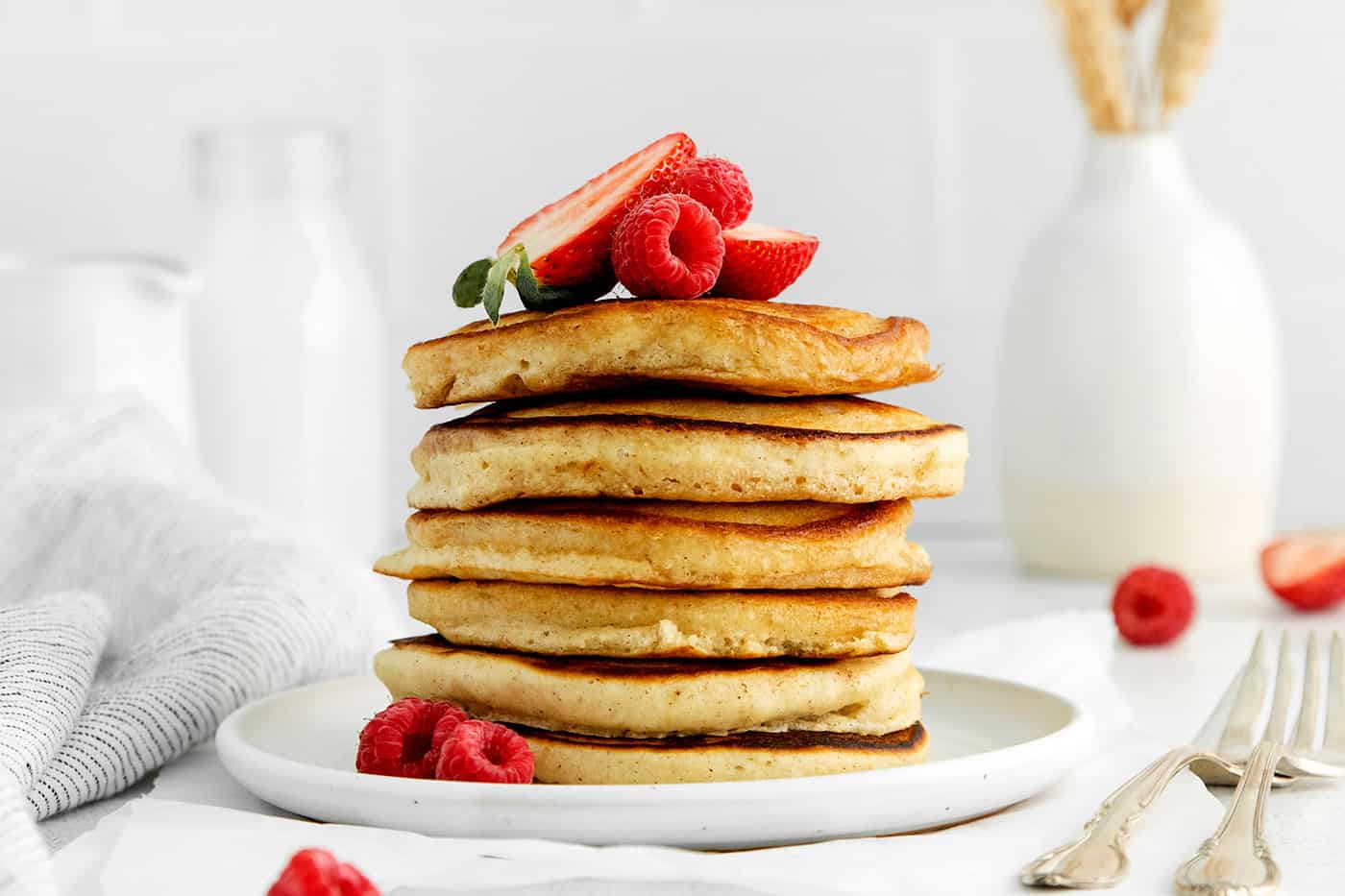 A stack of homemade pancakes topped with strawberries