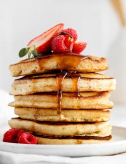 A stack of buttermilk pancakes with fresh strawberries