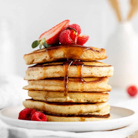 A stack of buttermilk pancakes with fresh strawberries