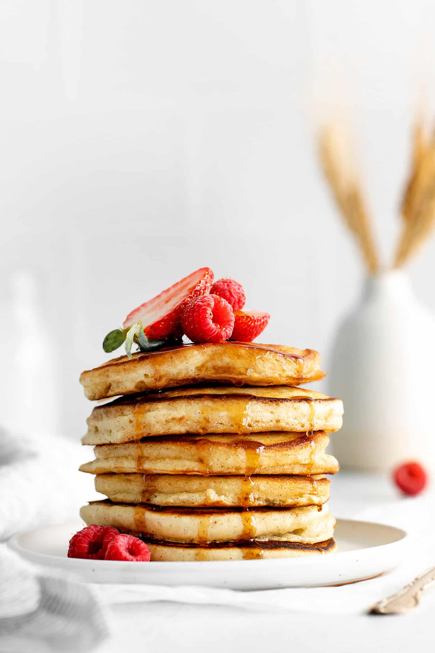 A stack of buttermilk pancakes topped with strawberries