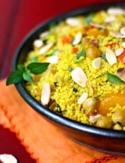 a bowl of orange couscous with almonds and chickpeas