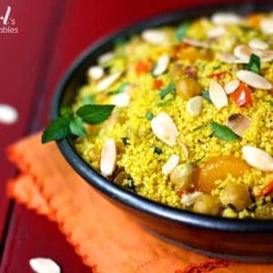 a bowl of orange couscous with almonds and chickpeas