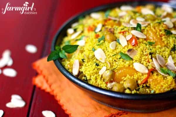 a bowl of orange couscous with almonds and chickpeas