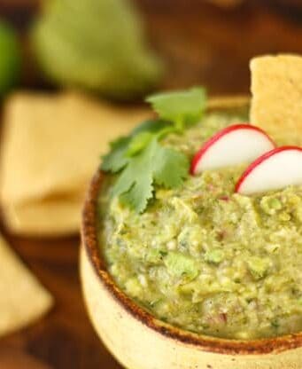 a pottery bowl of guacamole with tortilla chips