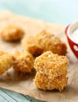 Baked chicken nuggets on parchment paper with a bowl of homemade ranch dip