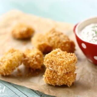 Baked chicken nuggets on parchment paper with a bowl of homemade ranch dip