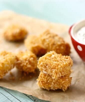 Baked chicken nuggets on parchment paper with a bowl of homemade ranch dip