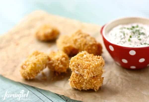 Baked chicken nuggets on parchment paper with a bowl of homemade ranch dip