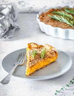 A slice of butternut squash tart with caramelized onions on a white plate