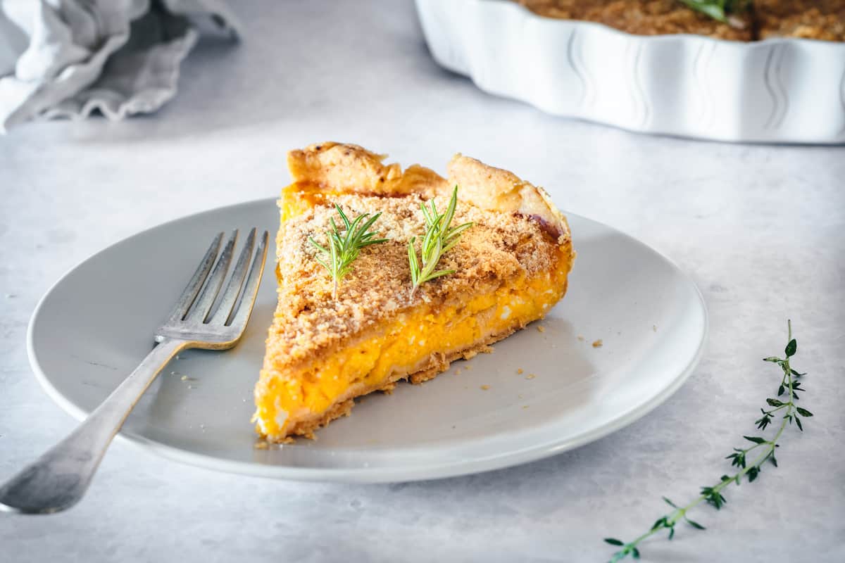 A slice of butternut squash tart with caramelized onions on a white plate
