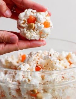 Hands rolling marshmallow popcorn ball.