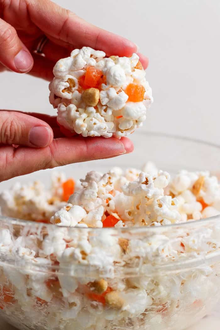 Hands rolling marshmallow popcorn ball.