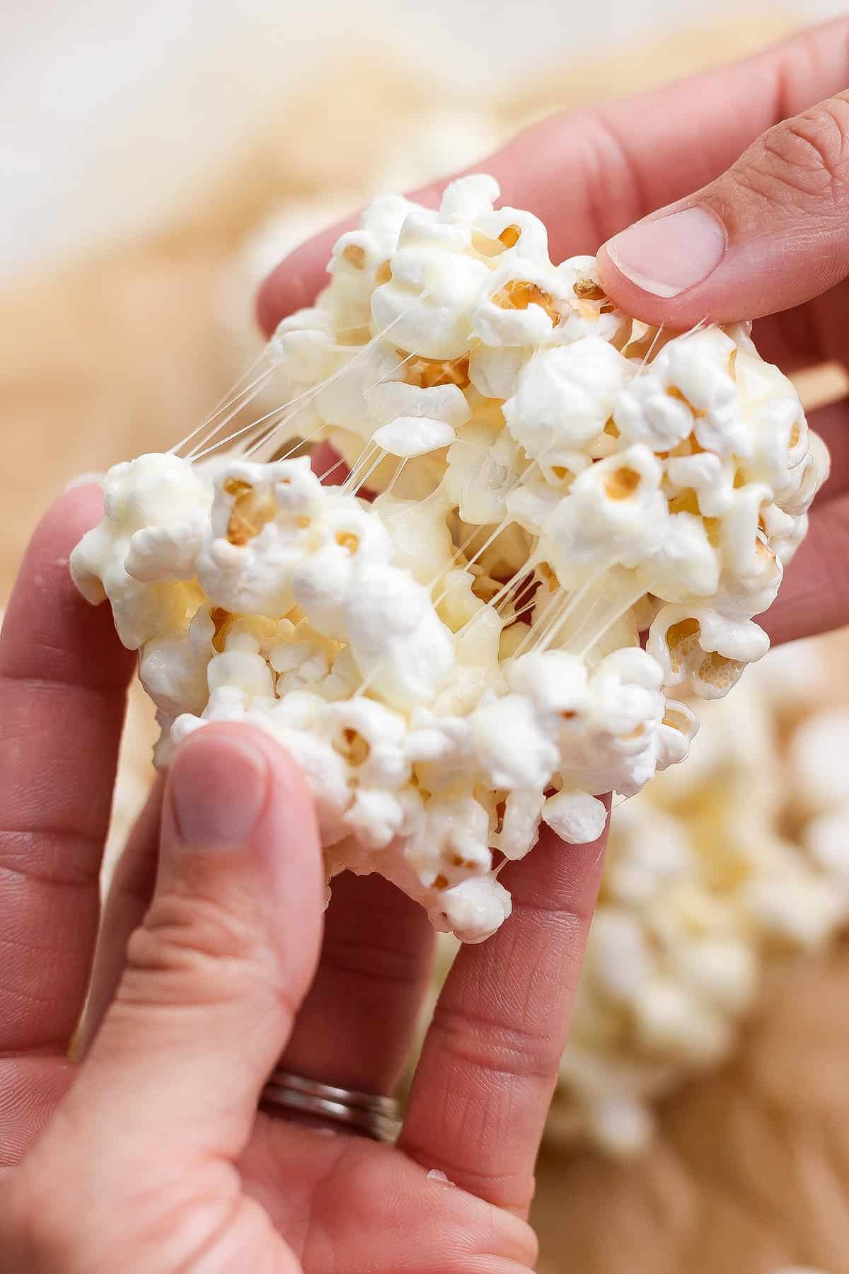 Hand pulling apart chewy marshmallow popcorn ball.