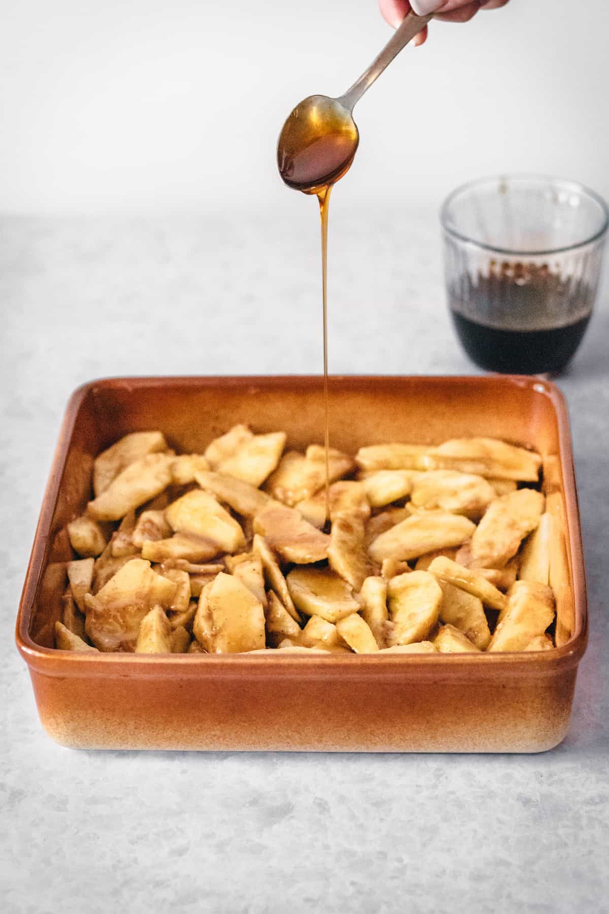 Caramel being poured over apple slices in a baking dish