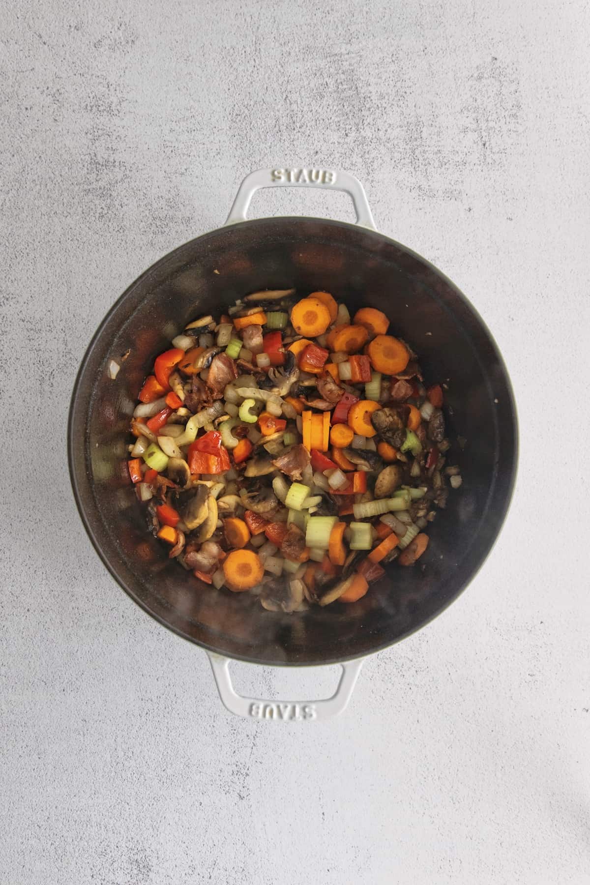 Chopped vegetables and bacon pieces in a black pot