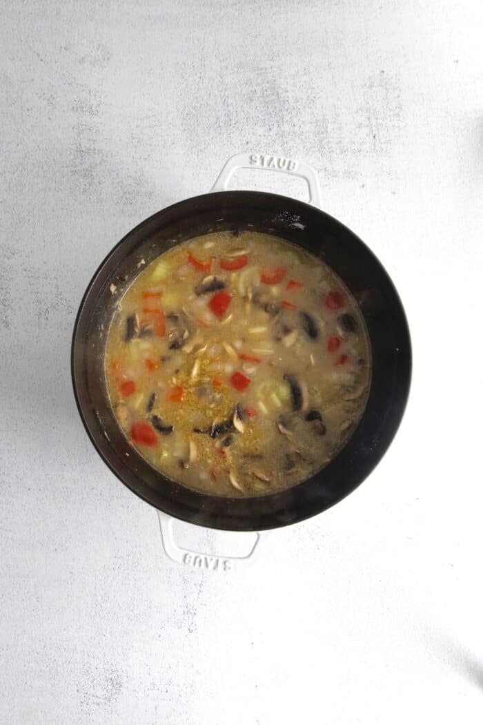 Vegetables and bacon with broth and half and half in a pot