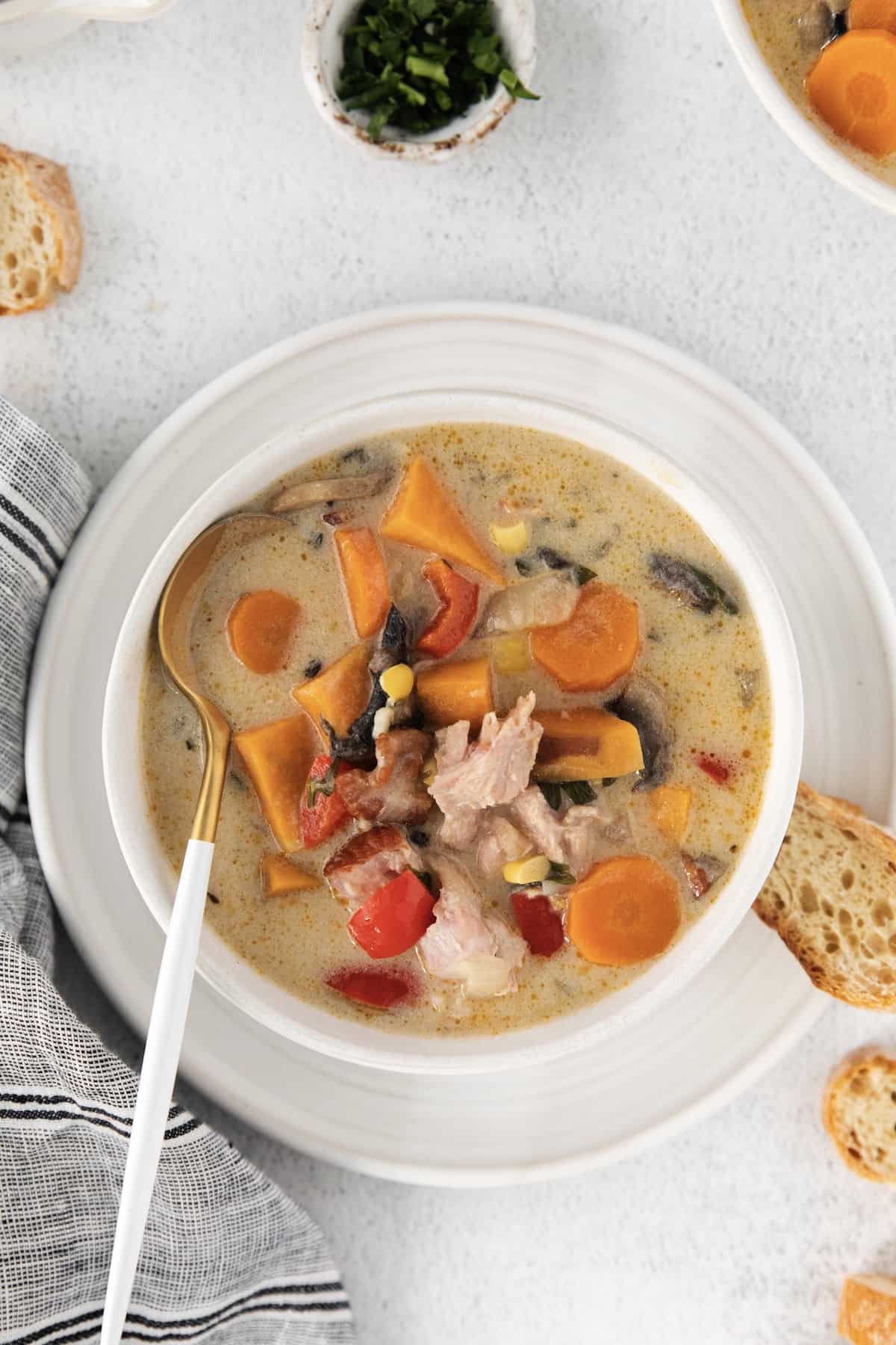 Overhead view of smoked turkey chowder in a white bowl with a spoon.