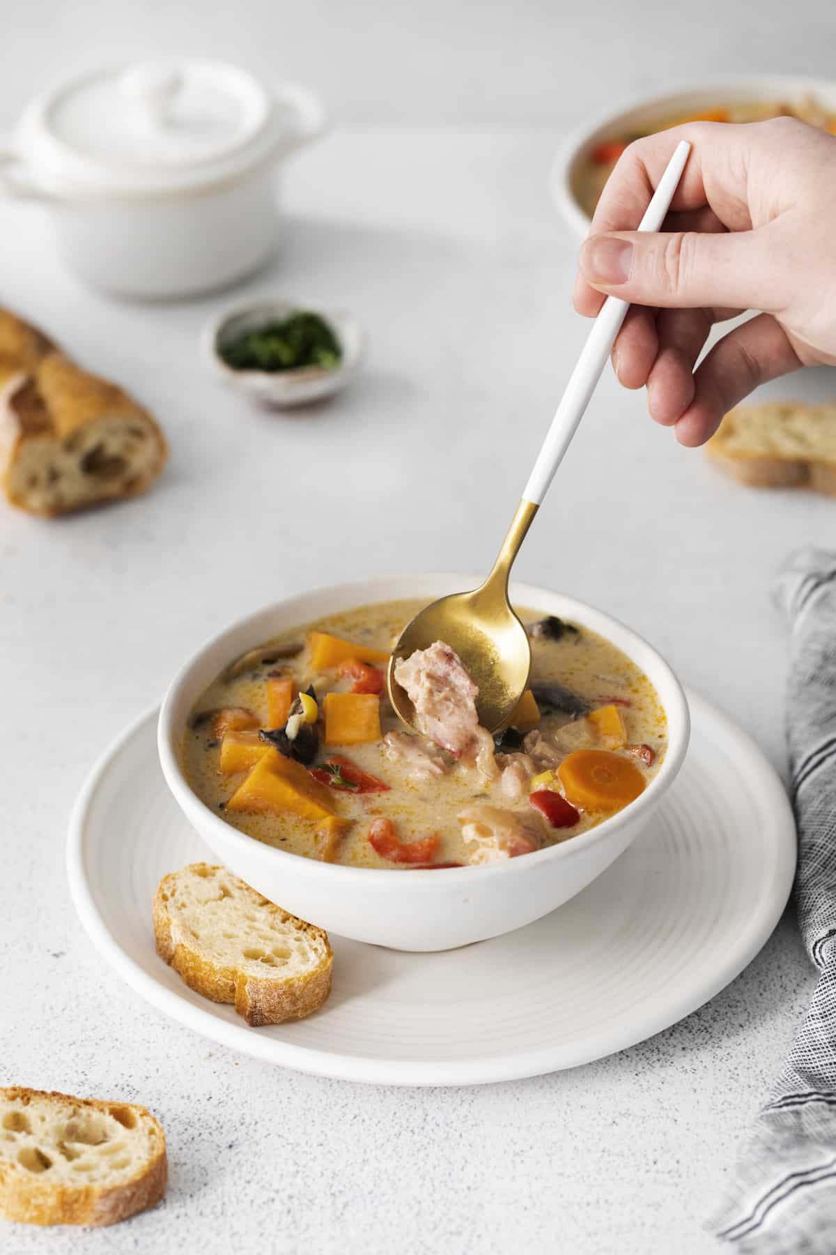 A spoon stirring a bowl of smoked turkey chowder