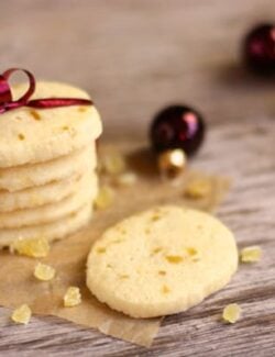 A stack of shortbread cookies with pieces of candied ginger wrapped in plum-colored ribbon