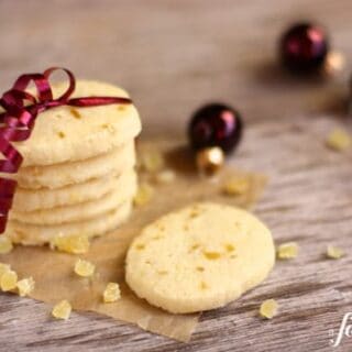 A stack of shortbread cookies with pieces of candied ginger wrapped in plum-colored ribbon