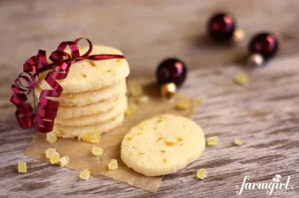 A stack of shortbread cookies with pieces of candied ginger wrapped in plum-colored ribbon