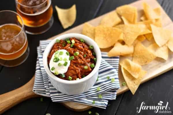 a white dish of Cheesy Beef Taco Dip with tortilla chips
