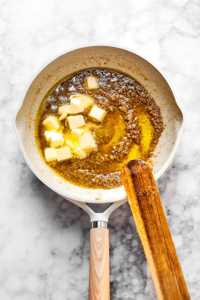 Butter added to pan of garlic, olive oil, and anchovies
