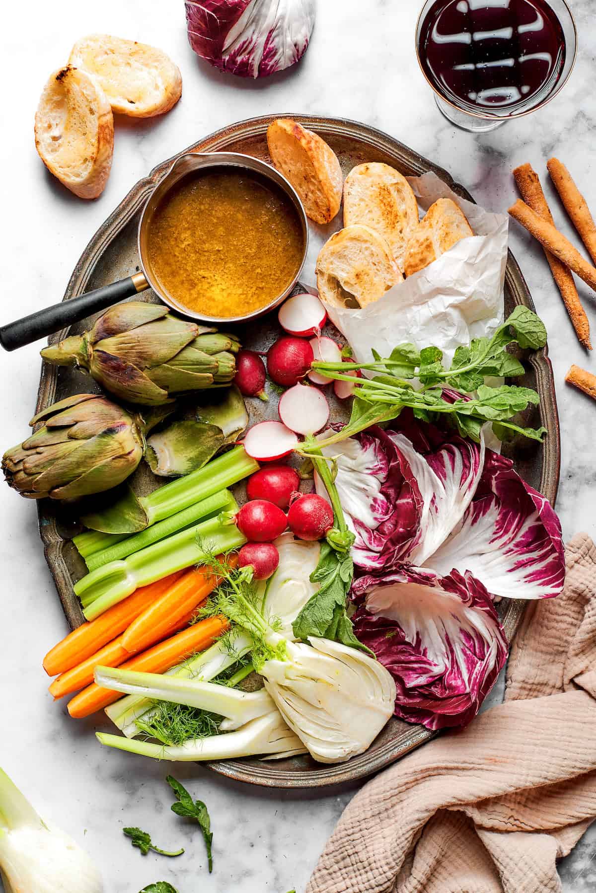 Overhead view of platter with bagna cauda, vegetables, and bread